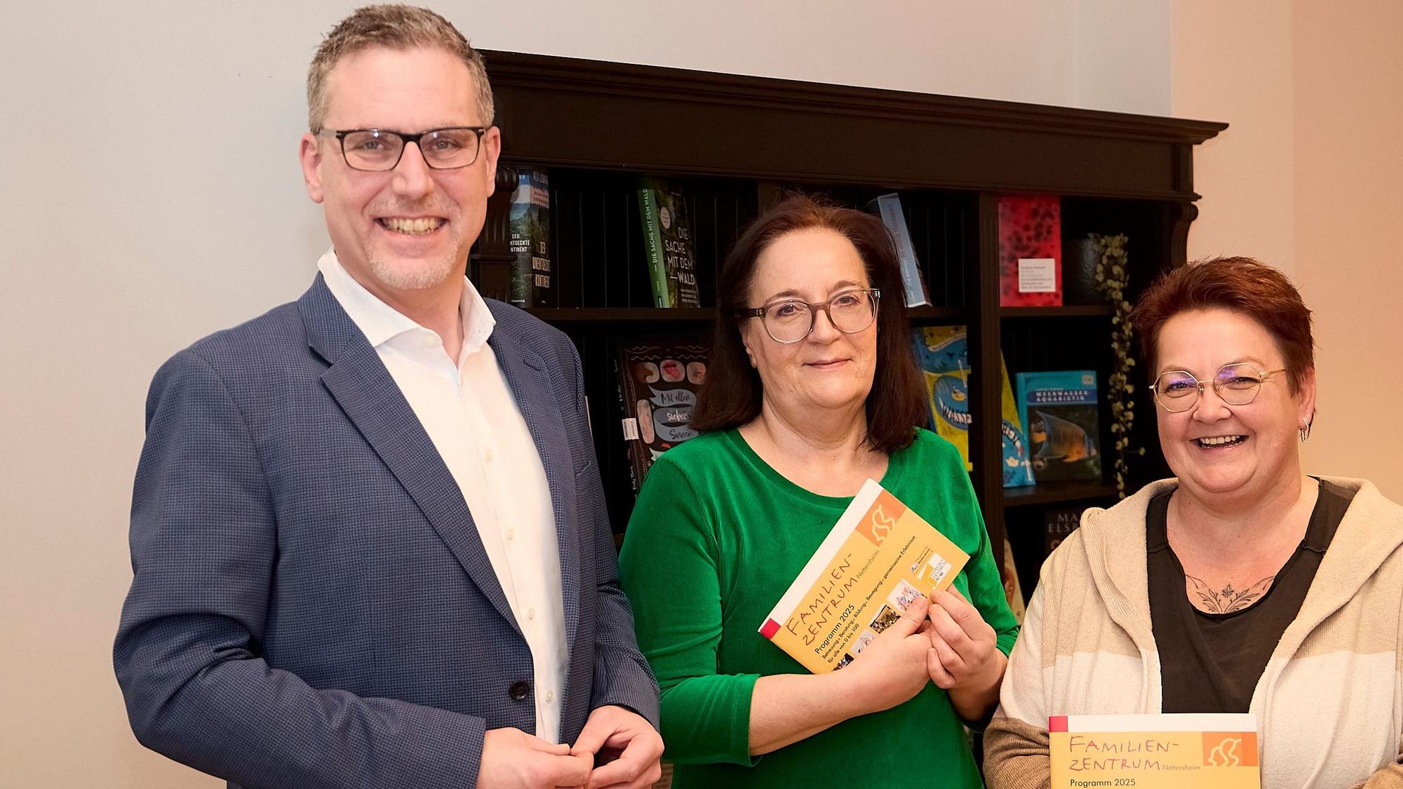 Iris Beging und Brigitte Wies halten das Programmheft in der Hand, Norbert Crump steht links daneben.
