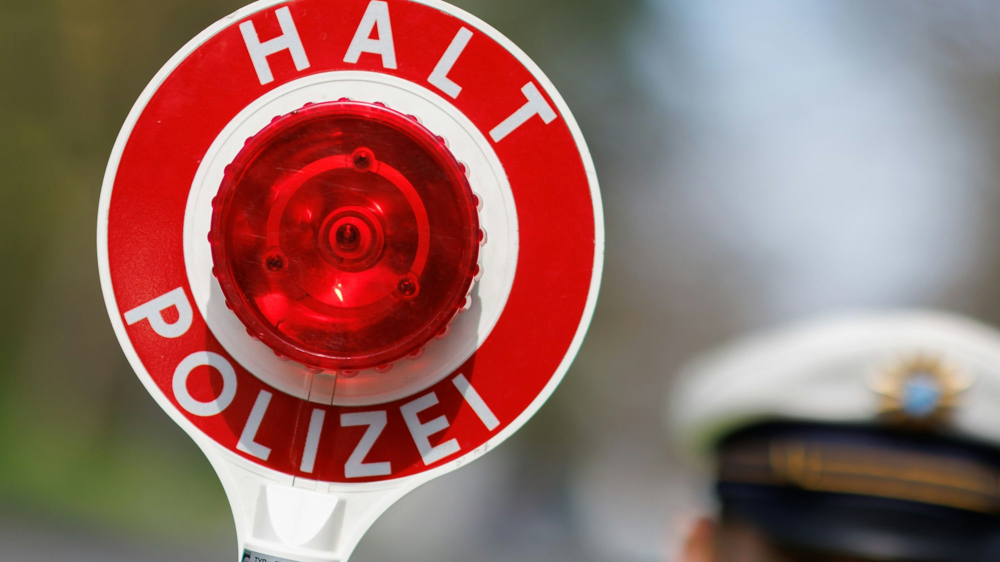 Das Bild zeigt eine Polizeikelle mit der Aufschrift "Halt Polizei".