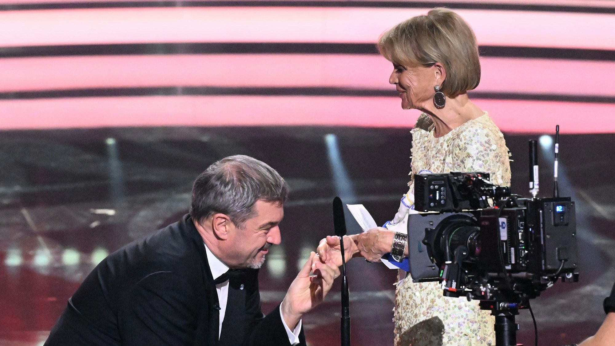 Markus Söder (CSU), Ministerpräsident von Bayern, kniet vor der Schauspielerin Uschi Glas bei der Verleihung des „Preis des Ministerpräsidenten“ auf der Bühne während der Show im Prinzregententheater.