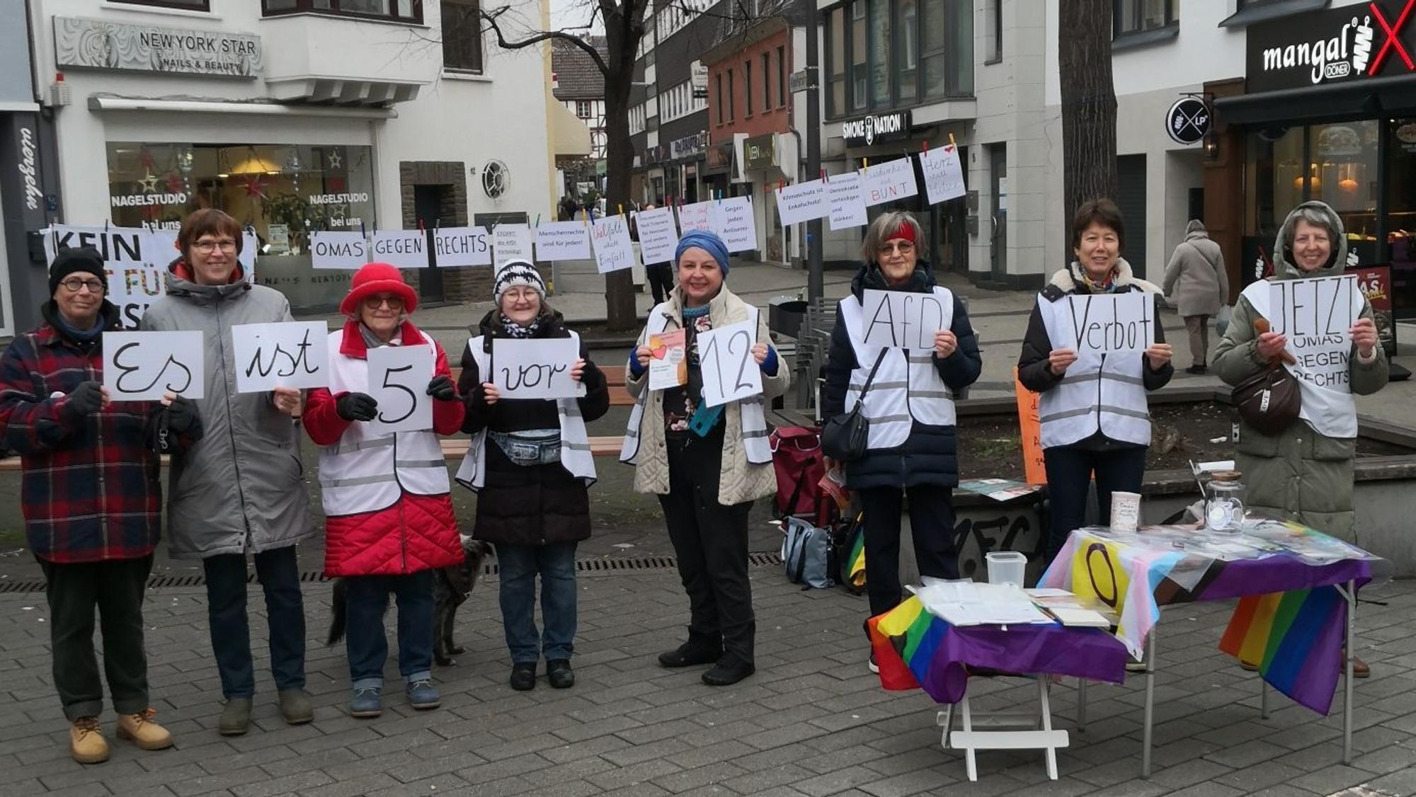 Acht Frauen halten Schilder hoch, deren Aufschrift den Satz „Es ist fünf vor zwölf. AfD-Verbot jetzt“ ergibt.