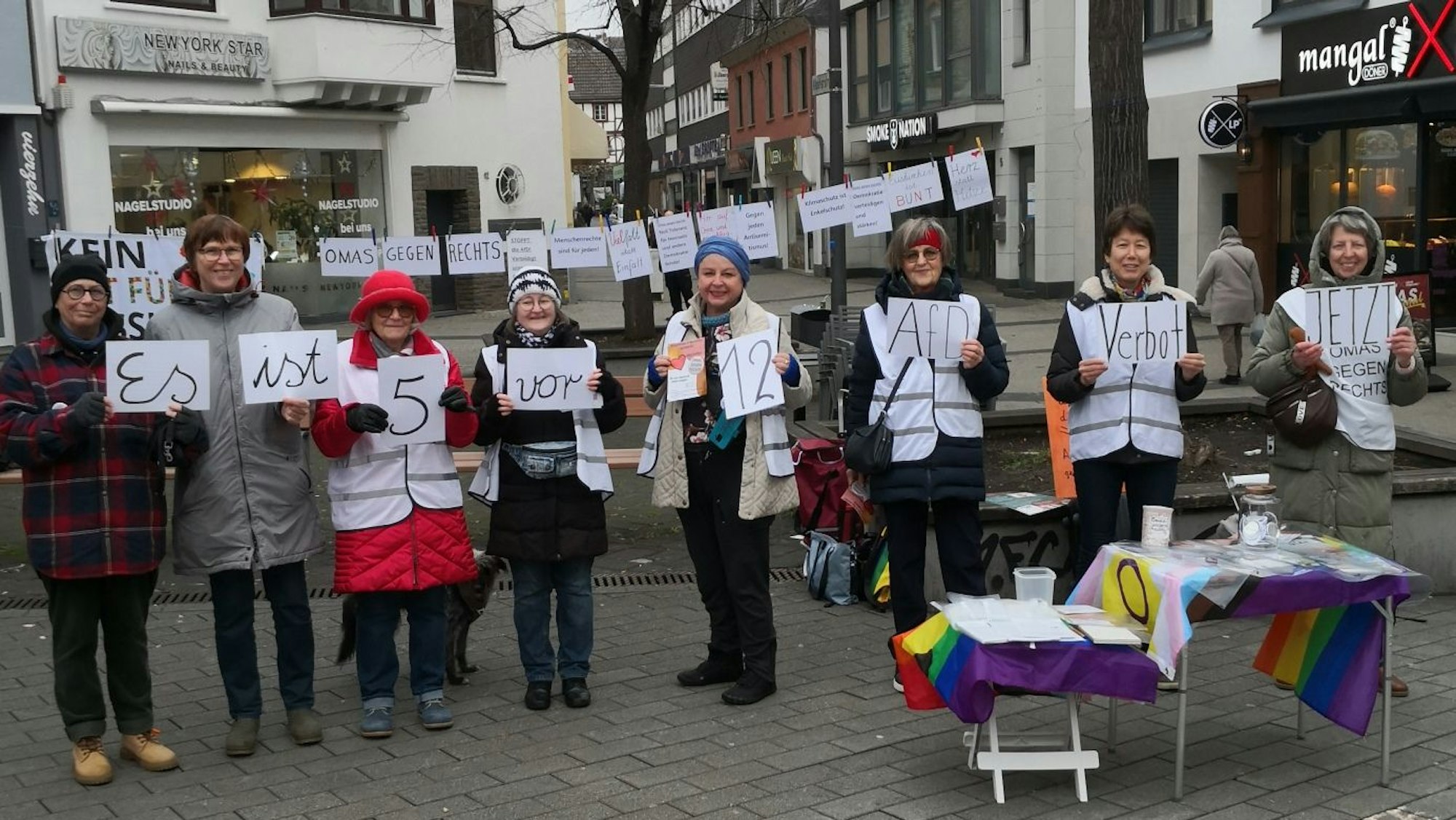 Acht Frauen halten Schilder hoch, deren Aufschrift den Satz „Es ist fünf vor zwölf. AfD-Verbot jetzt“ ergibt.