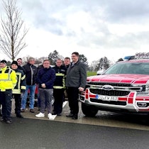 Eine große Gruppe Menschen steht vor drei Einsatzfahrzeugen der Rettungswache.