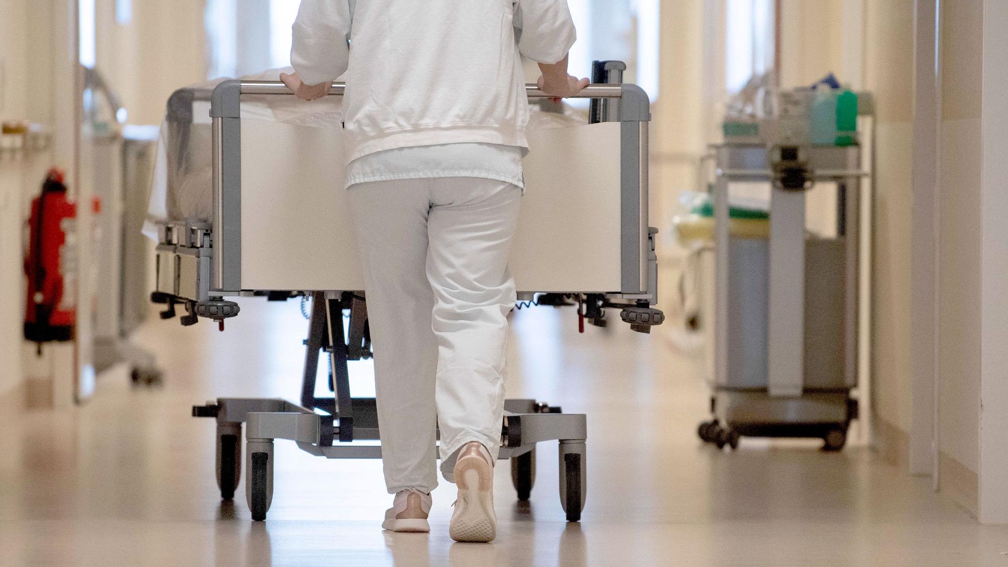 Eine Krankenpflegerin schiebt ein Krankenbett durch einen Krankenhausflur. (Archiv)