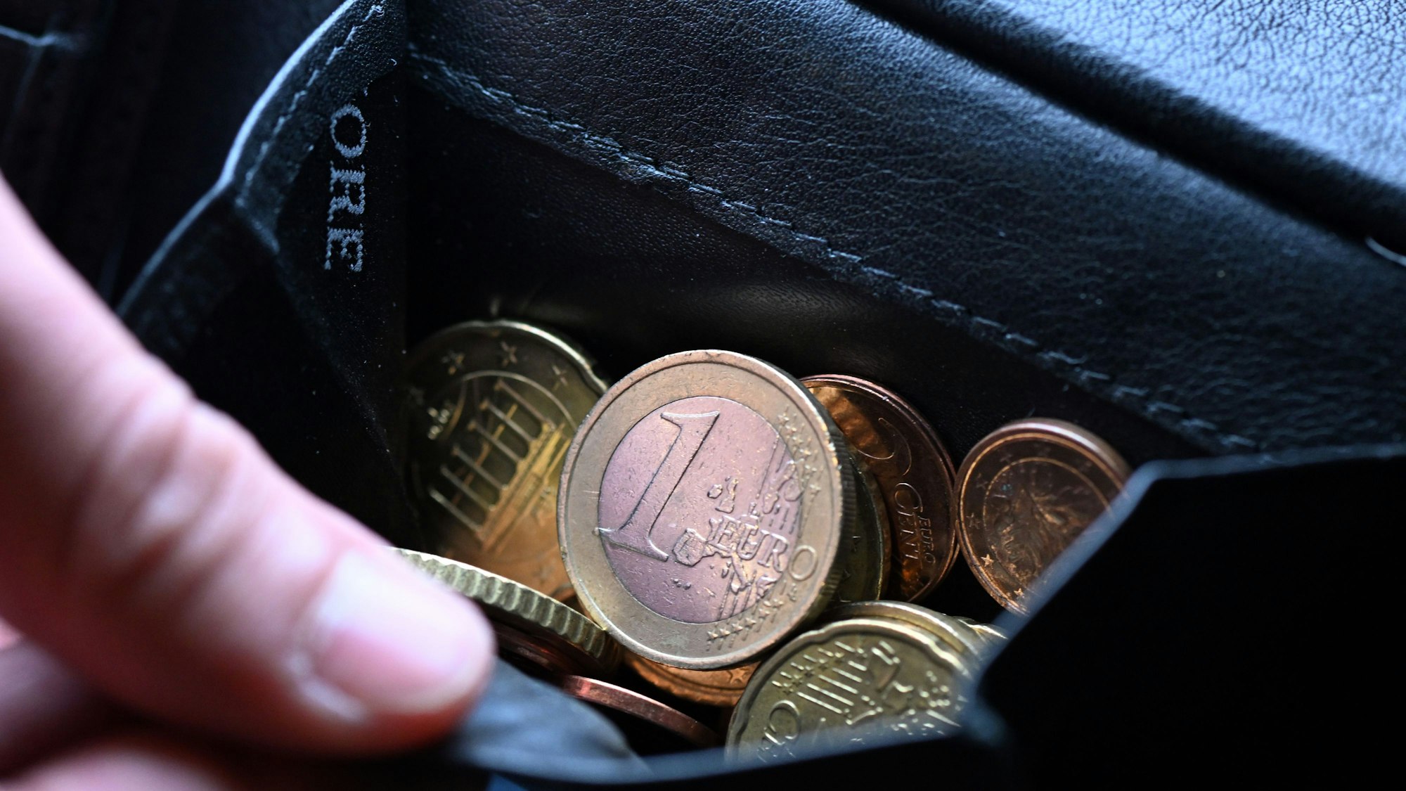 Eine Hand greift in einen Geldbeutel mit Münzen. (Archivbild)