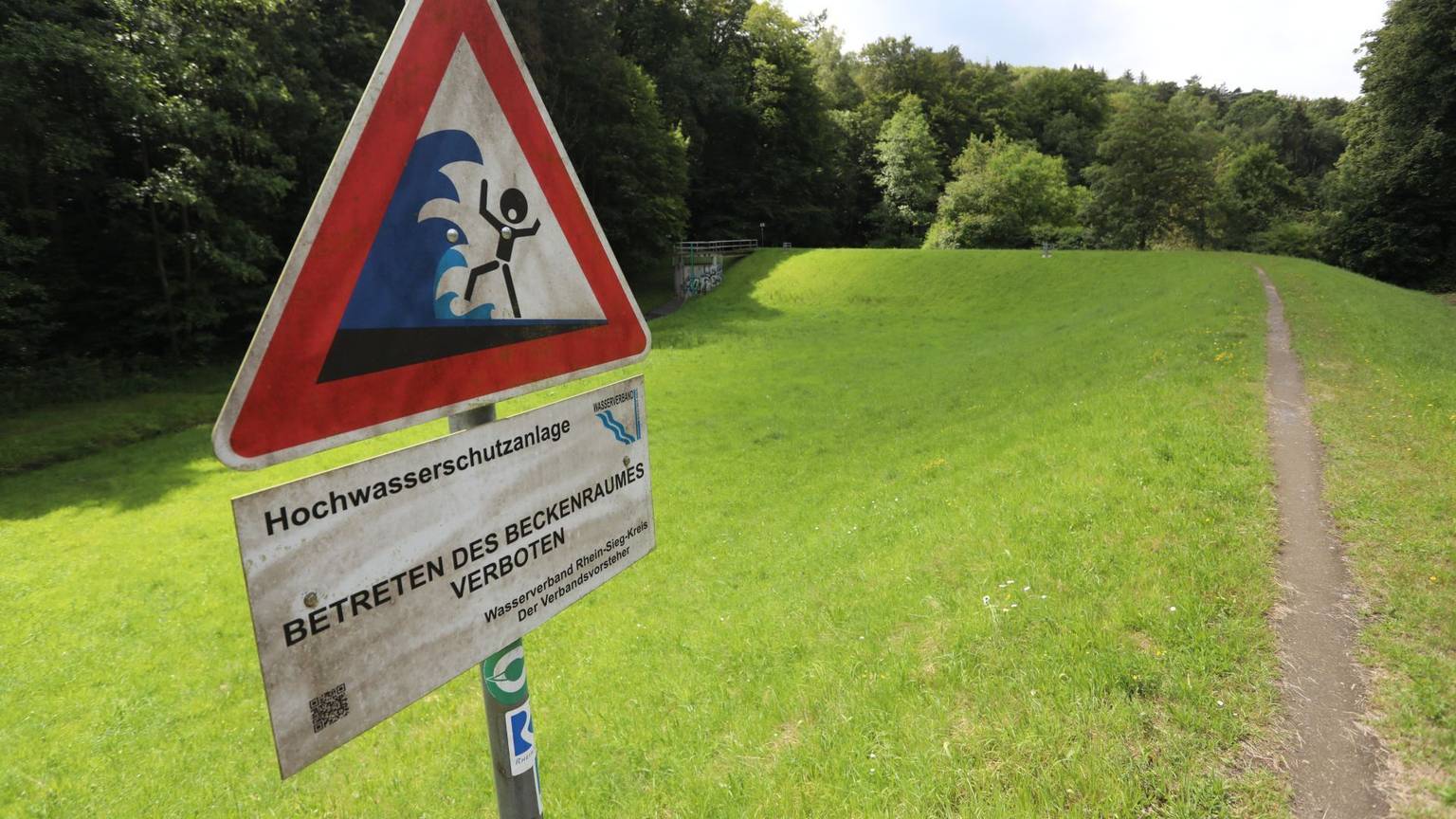 Ein Schild auf einem Damm warnt vor der Gefahr durch Hochwasser.