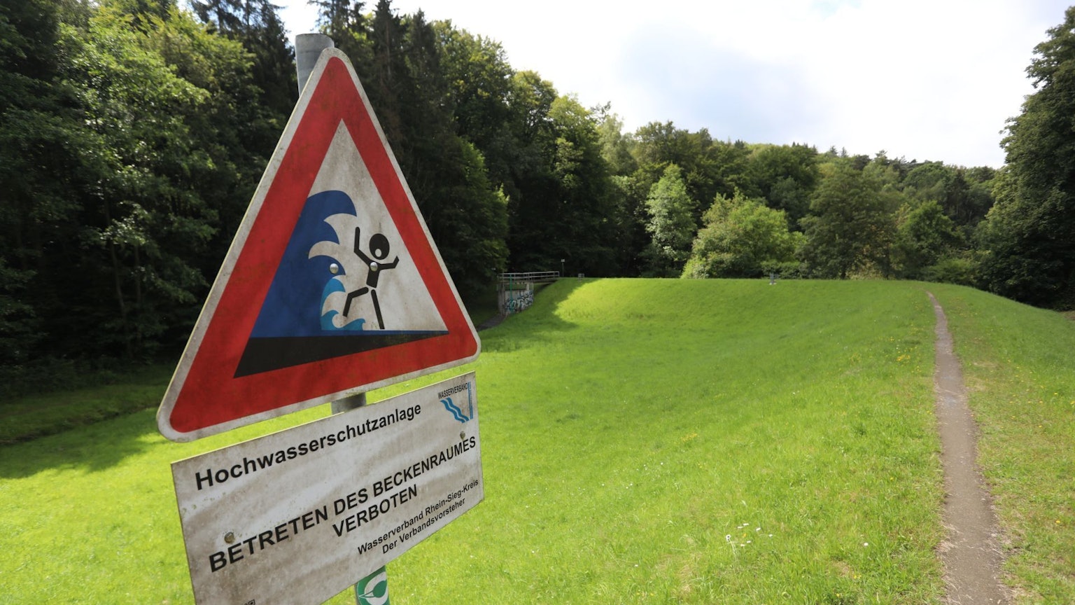Ein Schild auf einem Damm warnt vor der Gefahr durch Hochwasser.