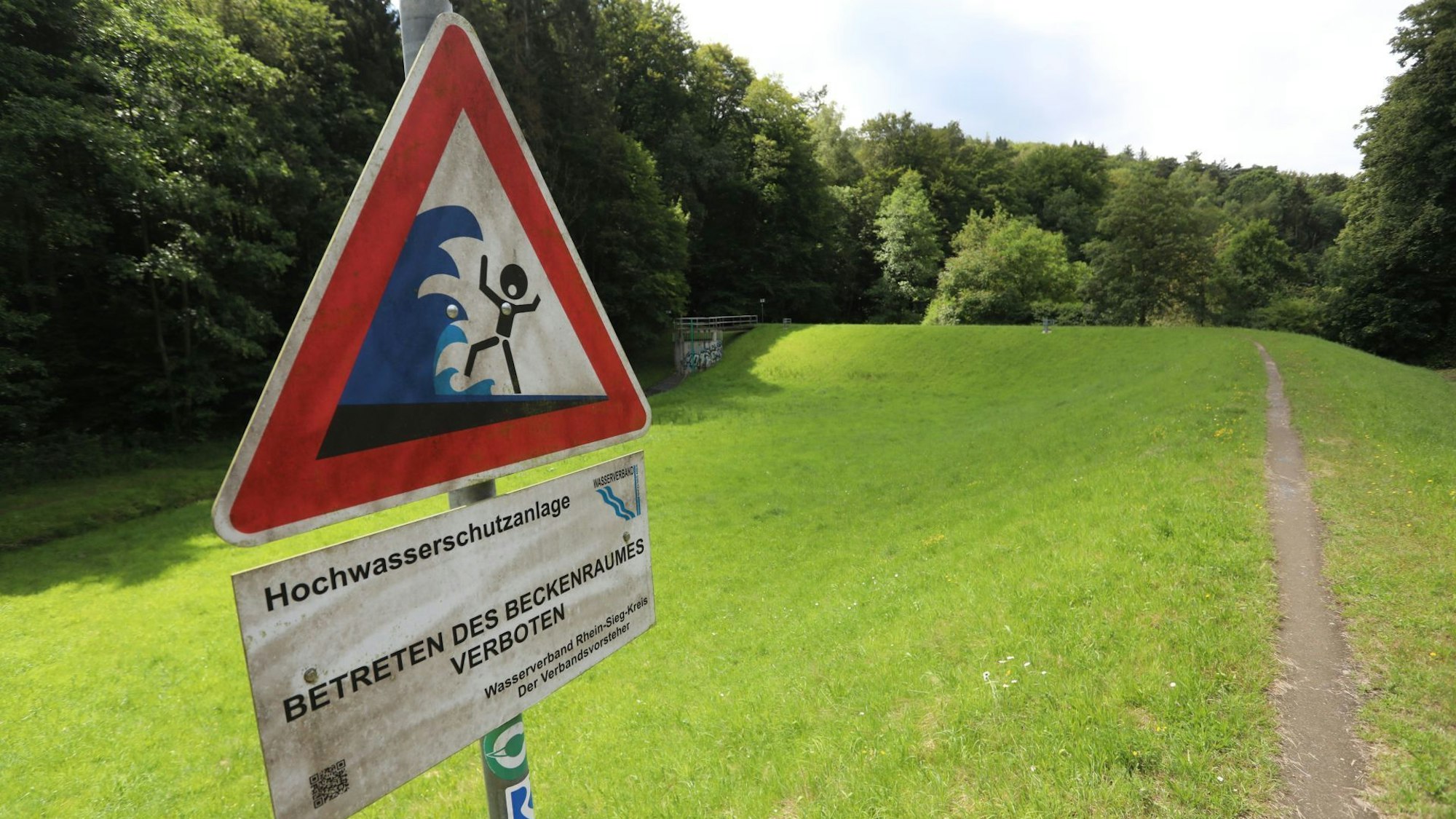 Ein Schild auf einem Damm warnt vor der Gefahr durch Hochwasser.
