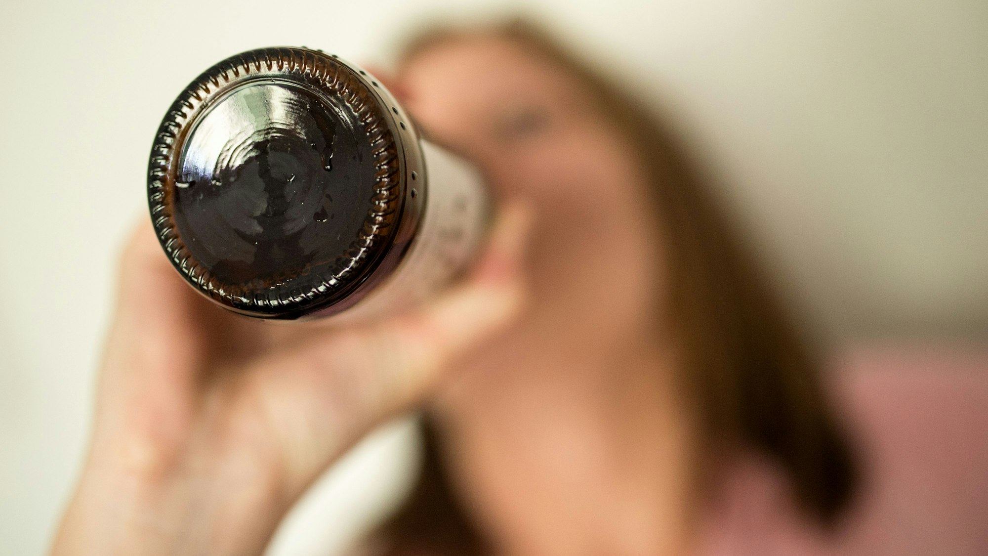 Eine Frau trinkt aus einer Flasche Bier.