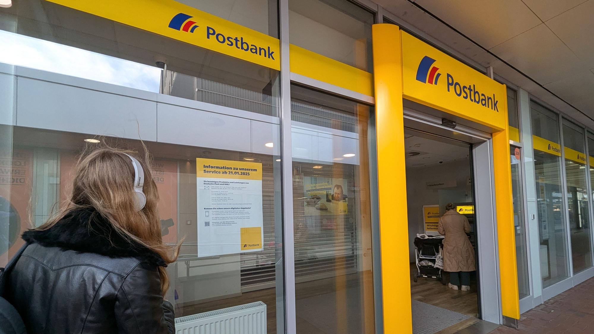 Das Foto zeigt eine Passantin vor dem Schaufenster der Postbankfiliale im Hürth-Park.