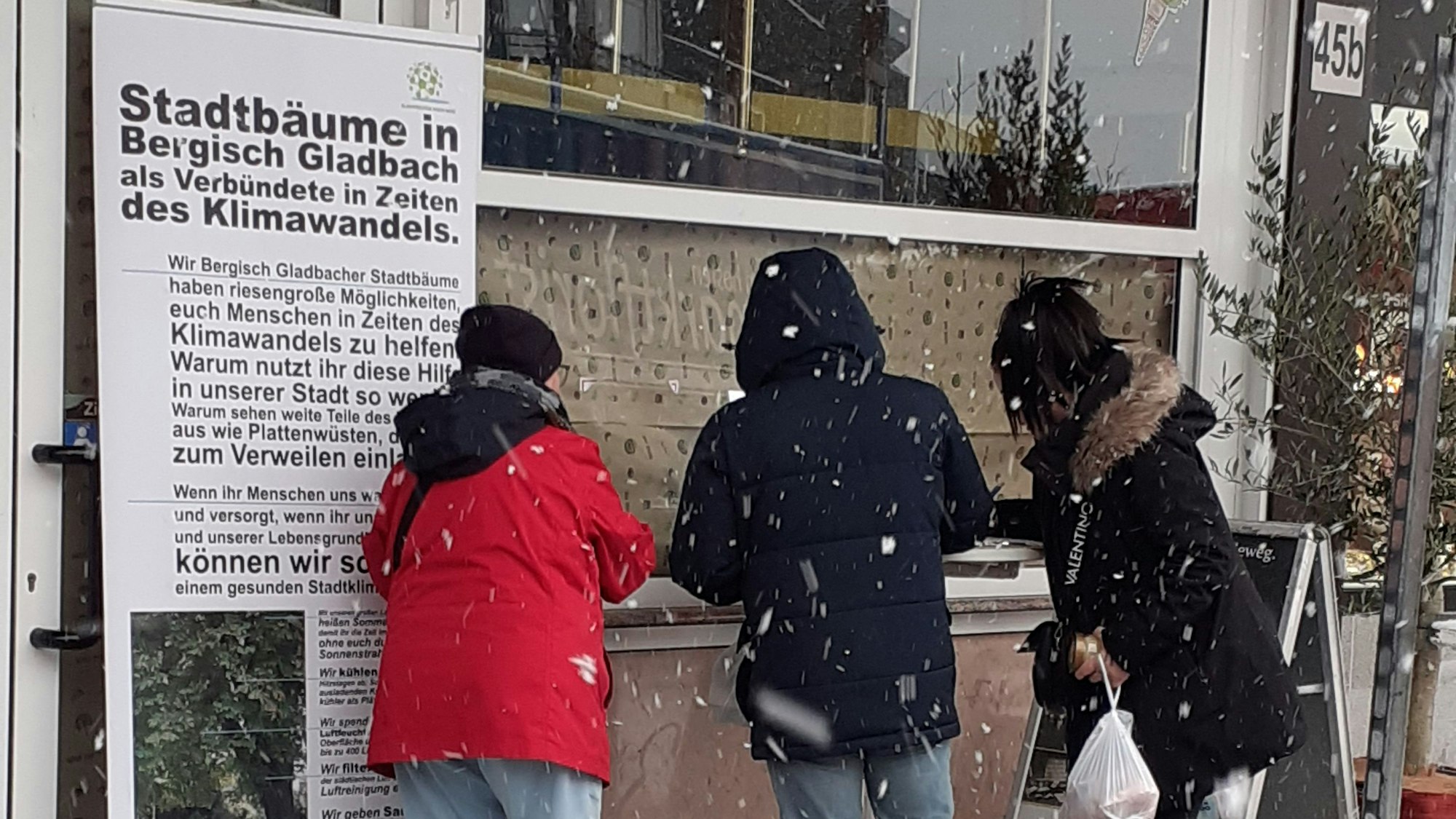 Neben einem Plakat stehen Leute, die die Petition unterschreiben.