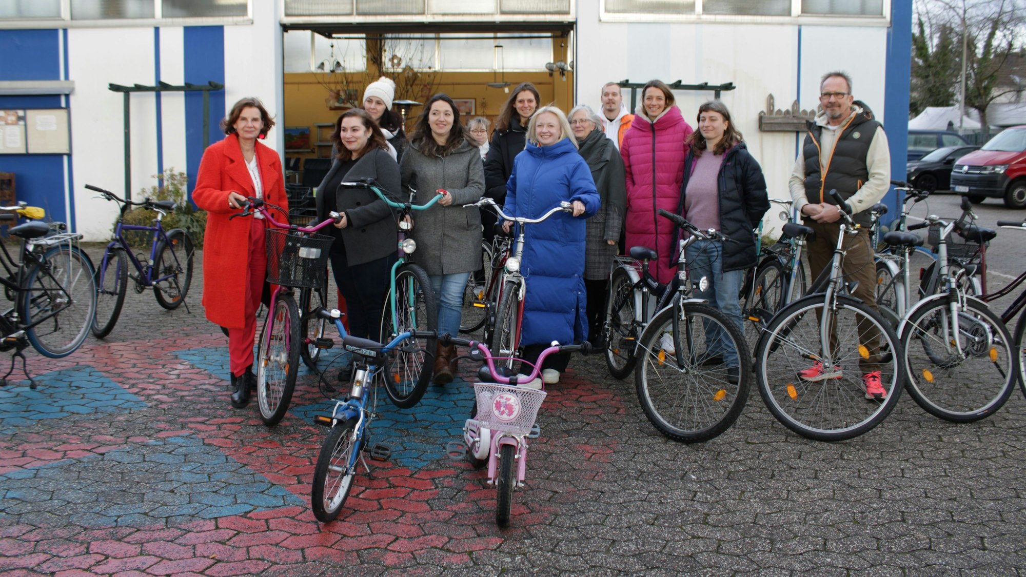 Zwölf Frauen und Männer stehen in einem Innenhof zwischen zahlreichen Fahrrädern, im Vordergrund zwei Kinderräder.
