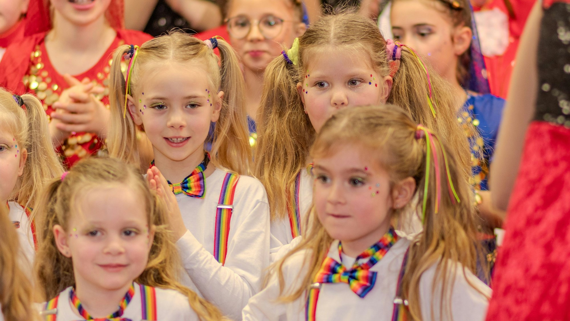 Eine Gruppe Mädchen mit bunten Fliegen und Zöpfen steht zusammen.