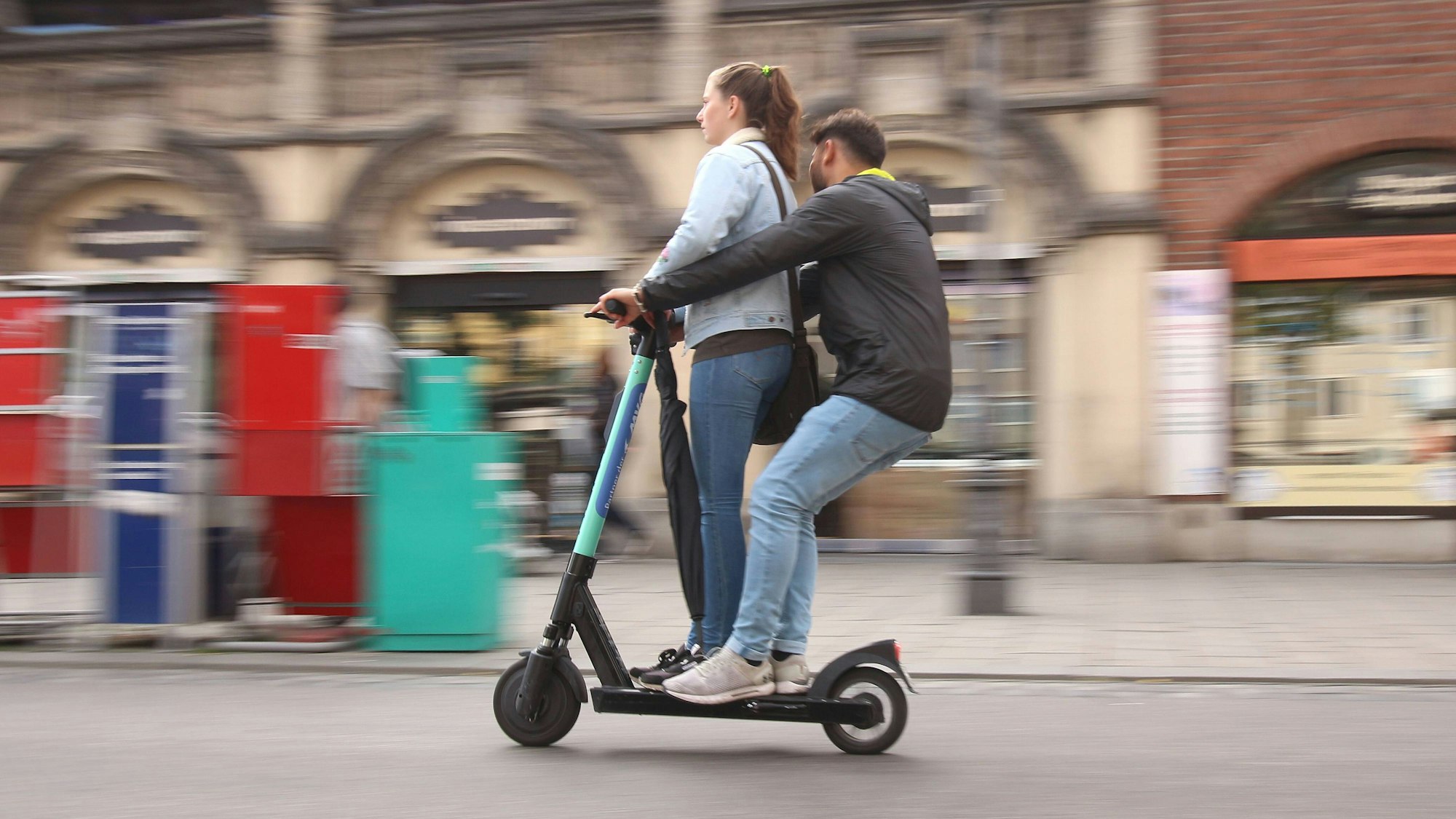 Zwei Personen fahren verbotenerweise auf einem E-Roller.