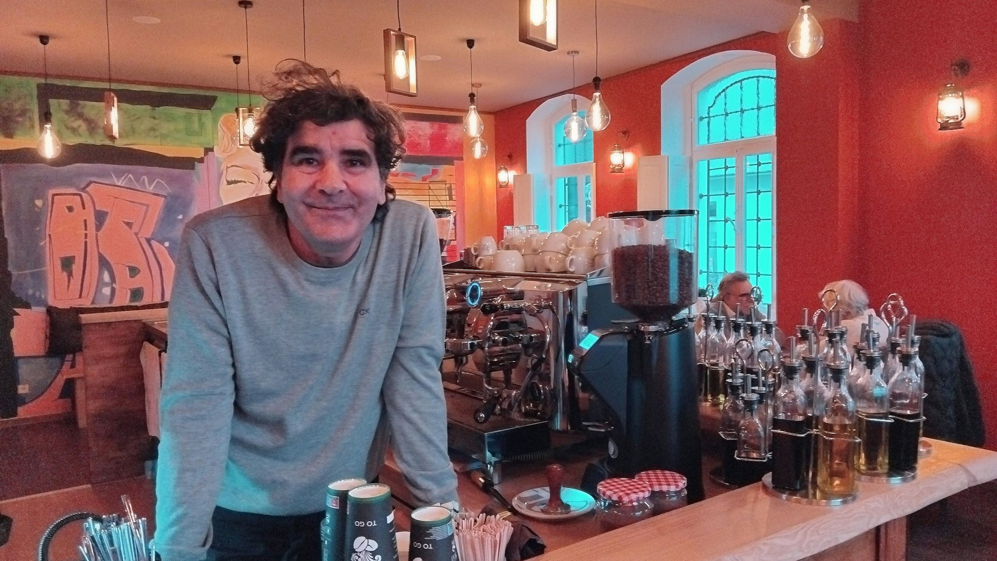 Ein Mann steht in einem Gastraum hinter der Theke