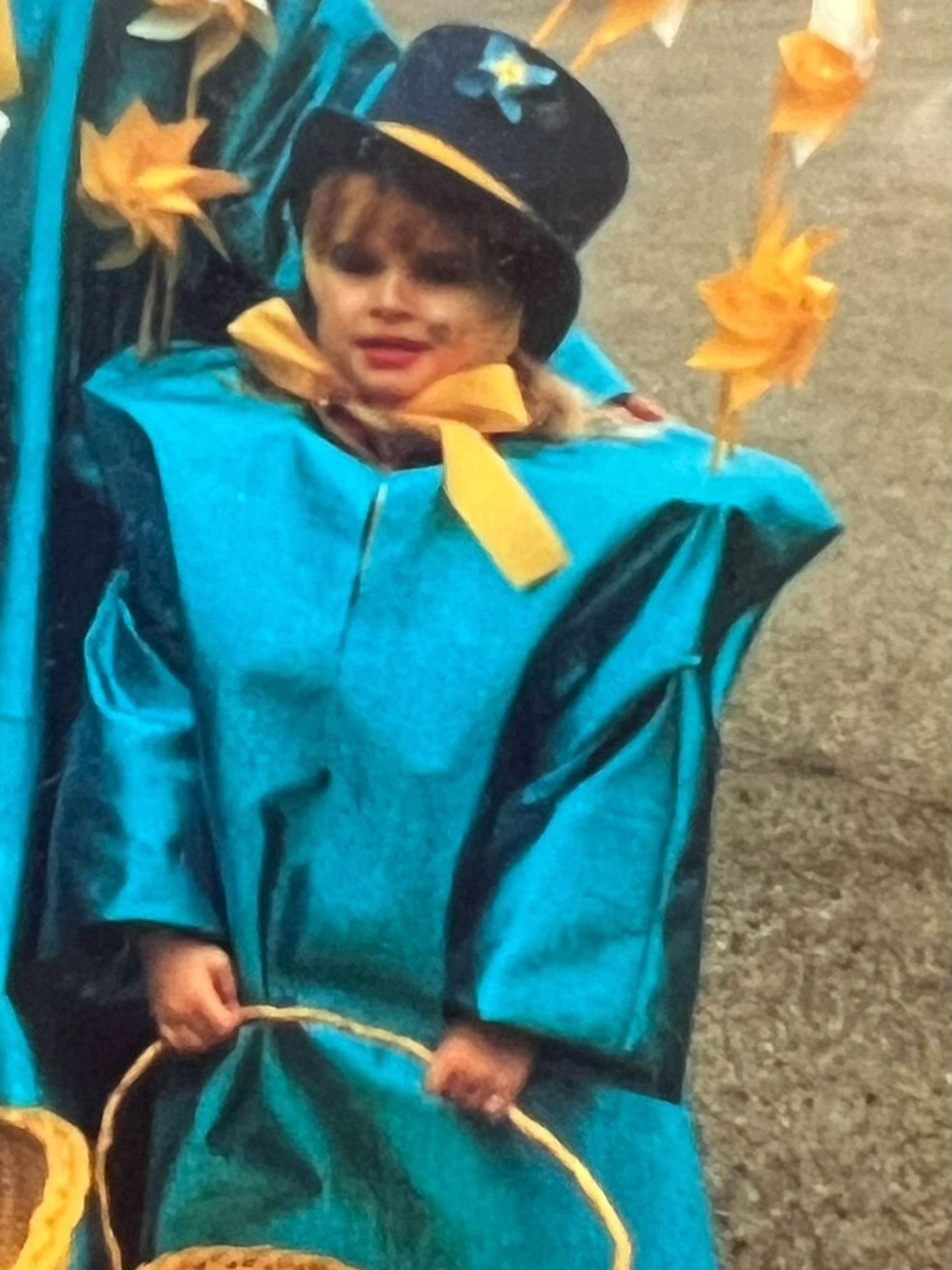 Stephanie Müller steht als Kind in einem blauen Kostüm am Rand eines Karnevalszugs.