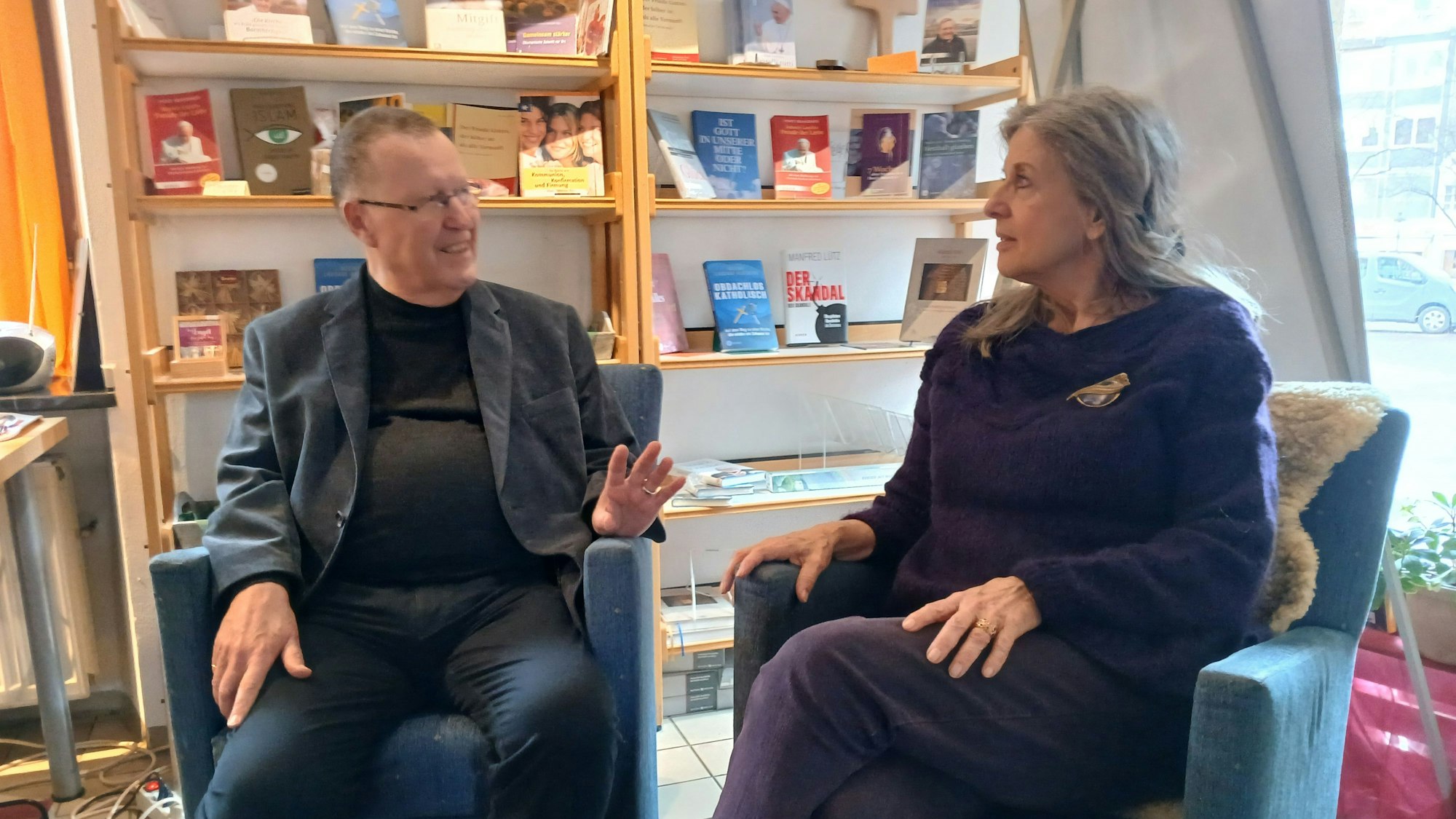 Ein Mann und eine Frau sitzen in Sesseln und unterhalten sich.