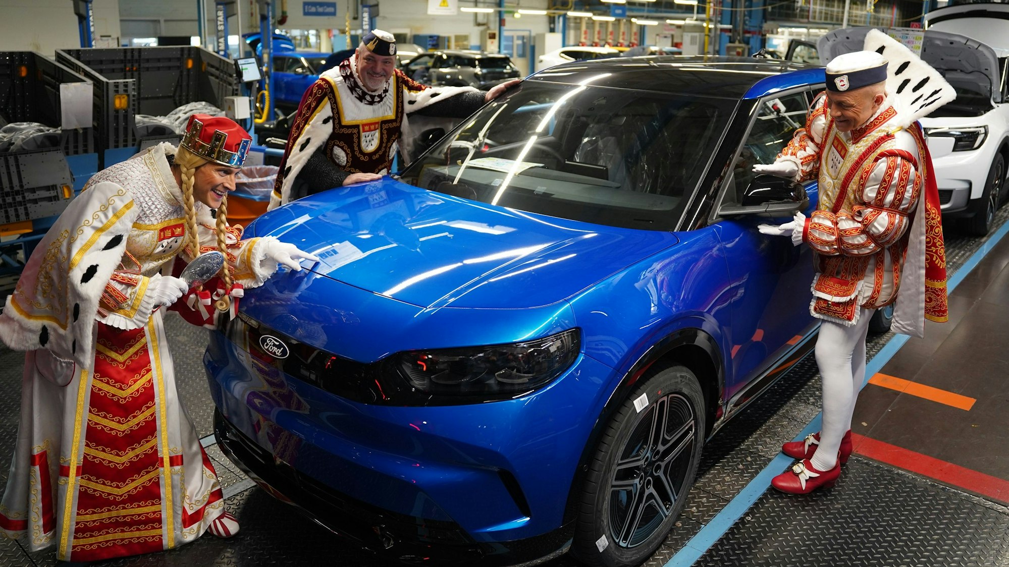 Das Dreigestirn steht an einem Auto der Marke Ford.