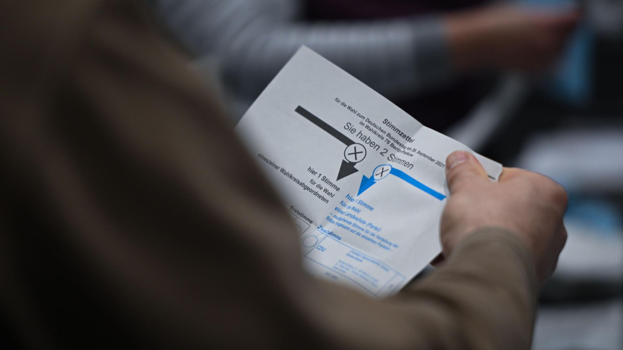 ARCHIV - 11.02.2024, Berlin: Ein Wahlhelfer hält während der Auszählung der Briefwahlstimmen in der Max-Schmeling-Halle einen Stimmzettel in der Hand.