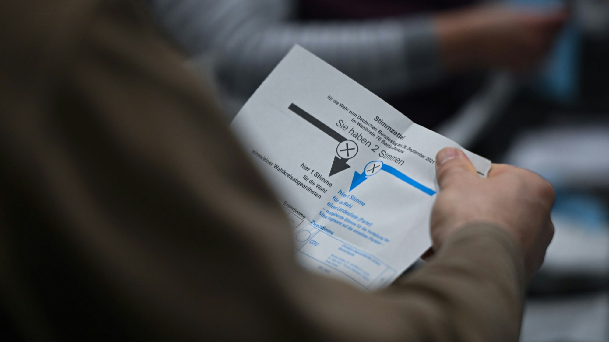 ARCHIV - 11.02.2024, Berlin: Ein Wahlhelfer hält während der Auszählung der Briefwahlstimmen in der Max-Schmeling-Halle einen Stimmzettel in der Hand.