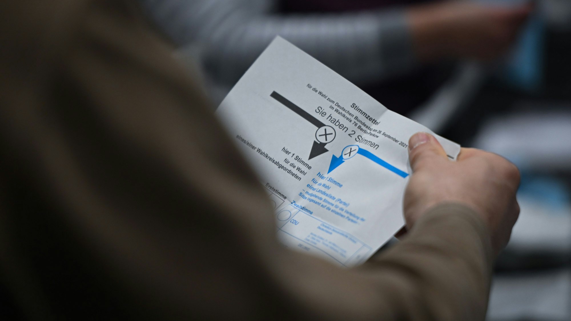 Ein Wahlhelfer hält während der Auszählung der Briefwahlstimmen einen Stimmzettel in der Hand.