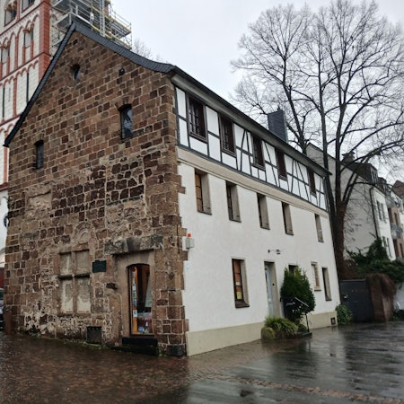 Ein altes Haus an einer Kirche.