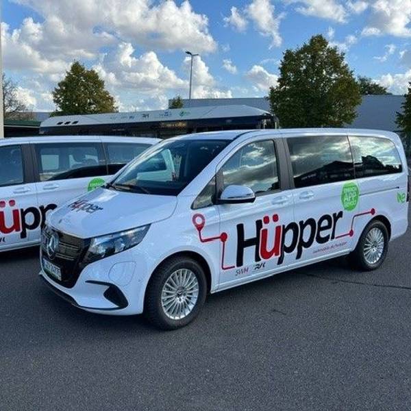 Das Foto zeigt zwei weiße Mercedes-Vans mit dem Hüpper-Logo auf den Türen.