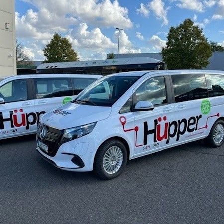 Das Foto zeigt zwei weiße Mercedes-Vans mit dem Hüpper-Logo auf den Türen.
