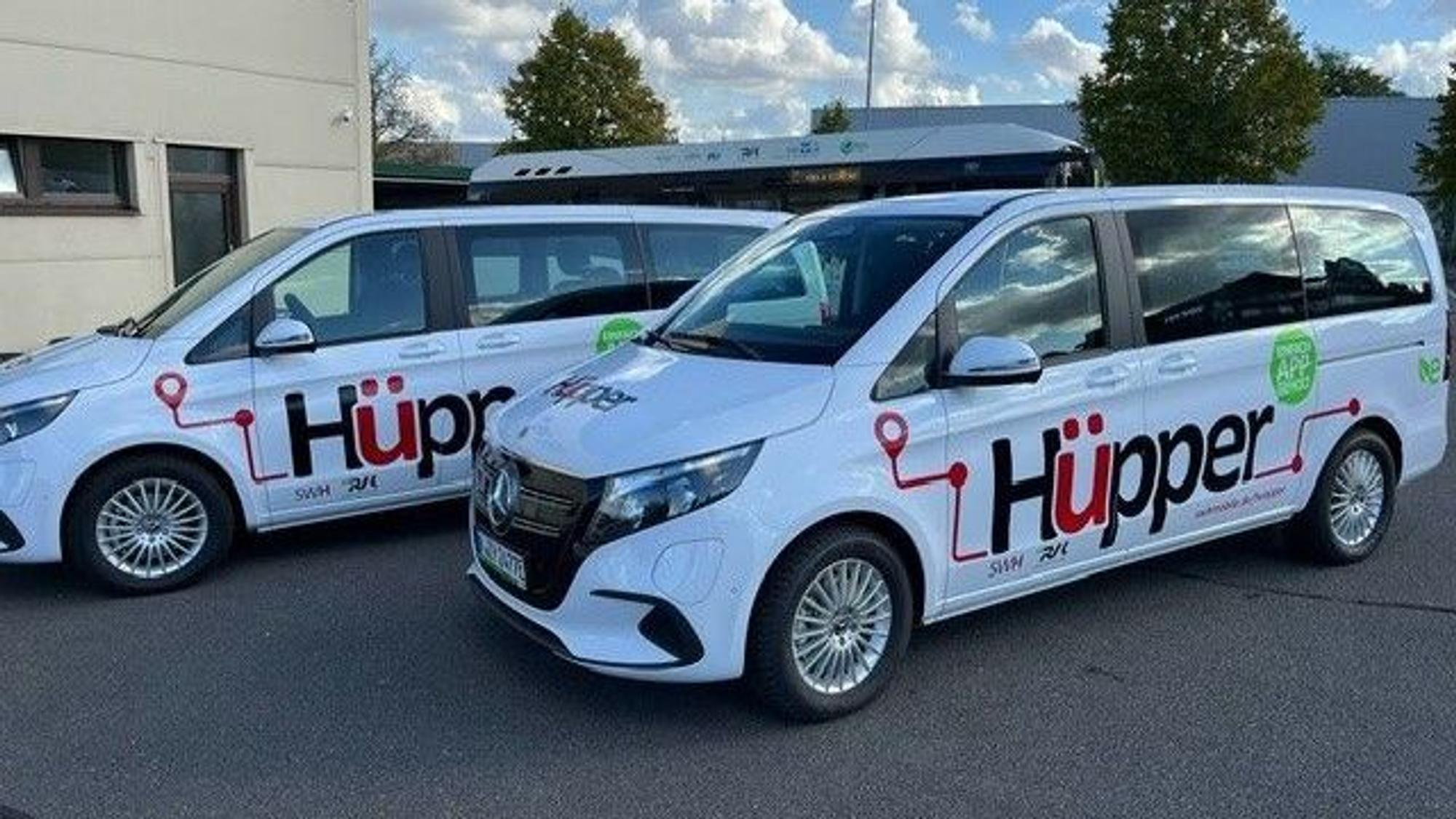 Das Foto zeigt zwei weiße Mercedes-Vans mit dem Hüpper-Logo auf den Türen.