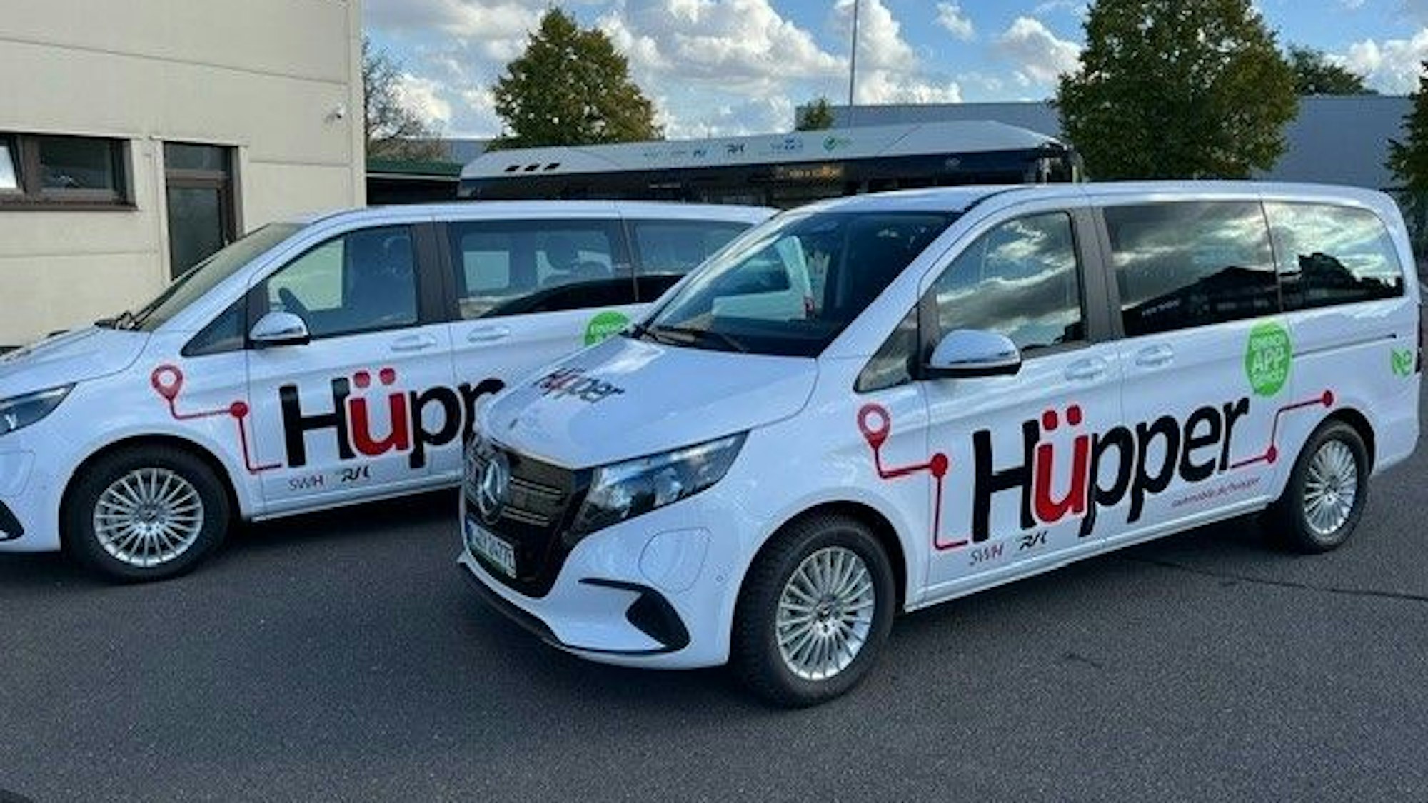 Das Foto zeigt zwei weiße Mercedes-Vans mit dem Hüpper-Logo auf den Türen.