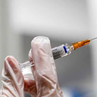 Zu sehen ist eine Spritze für eine Grippeschutzimpfung, gehalten von einer behandschuten Hand