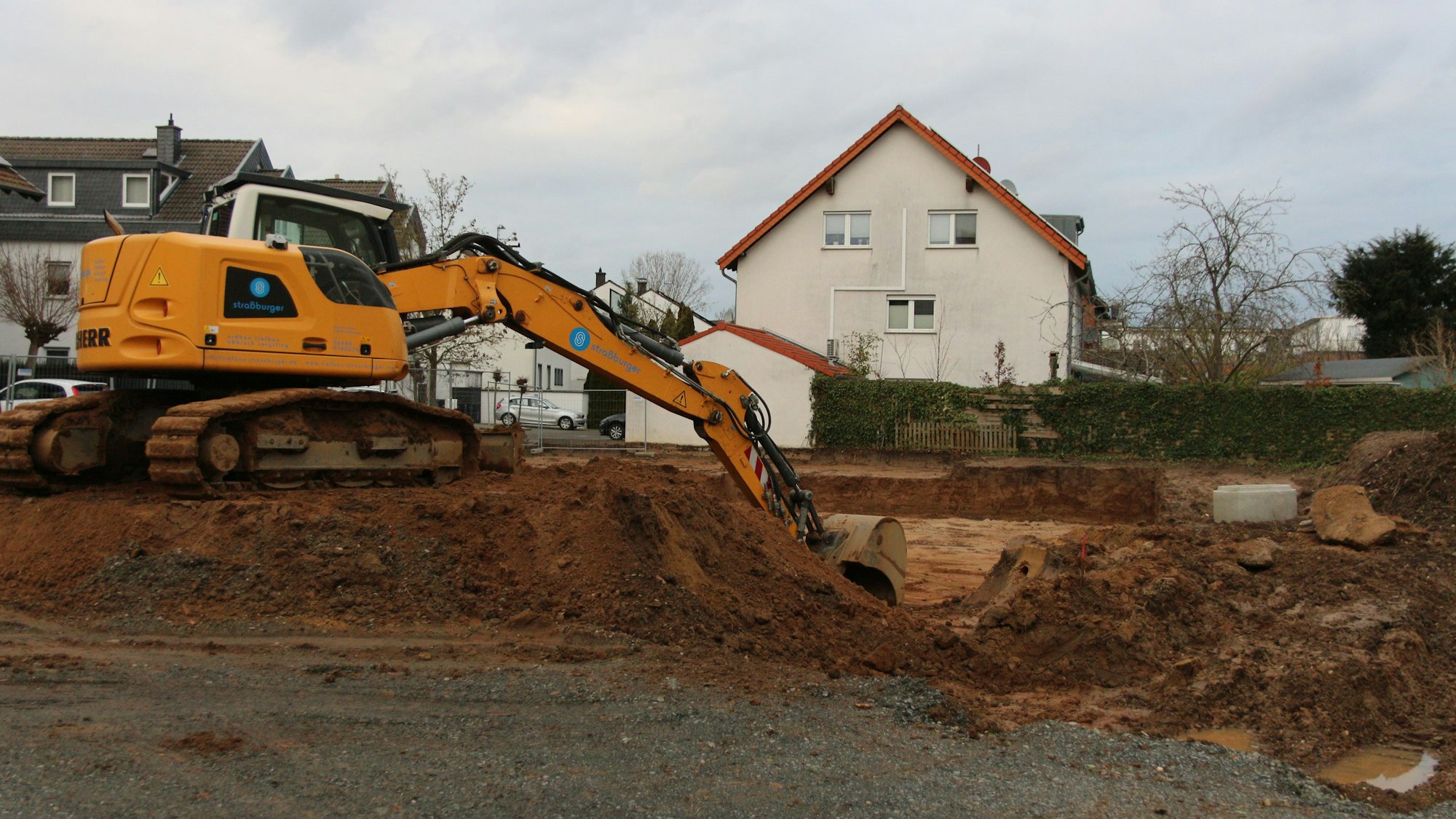 Eine Baggerschaufel gräbt sich durch das Erdreich.