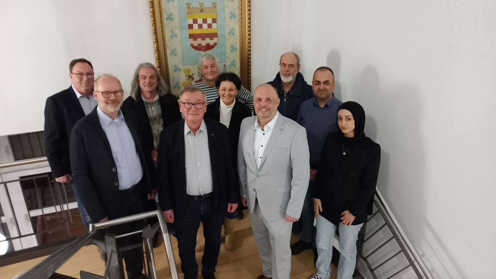 Eine Gruppe von Menschen steht vor dem Bergneustädter Stadtwappen.