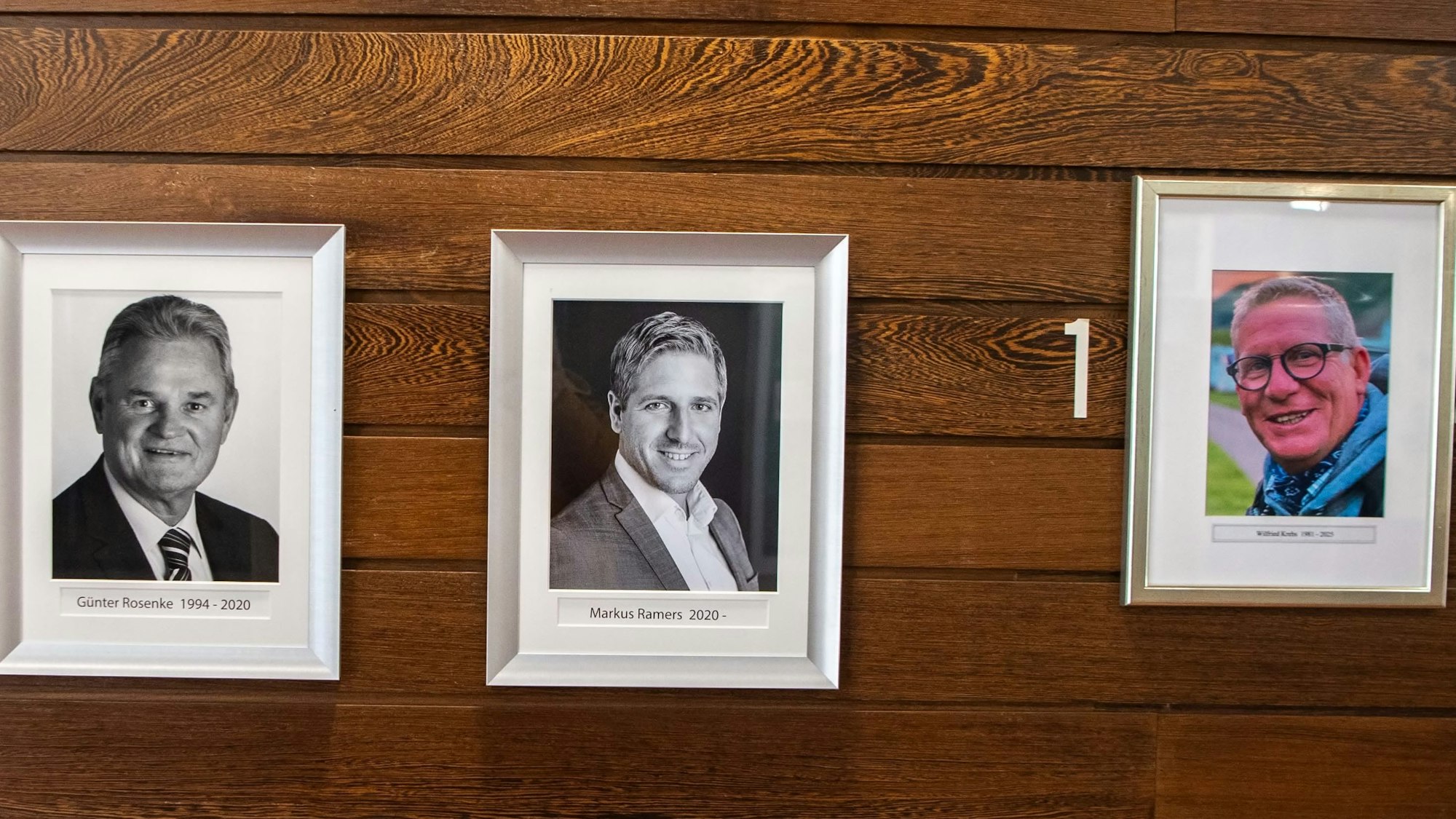 Neben den Bildern von Günter Rosenke und Markus Ramers hängt ein gerahmtes Porträt von Wilfried Krebs.