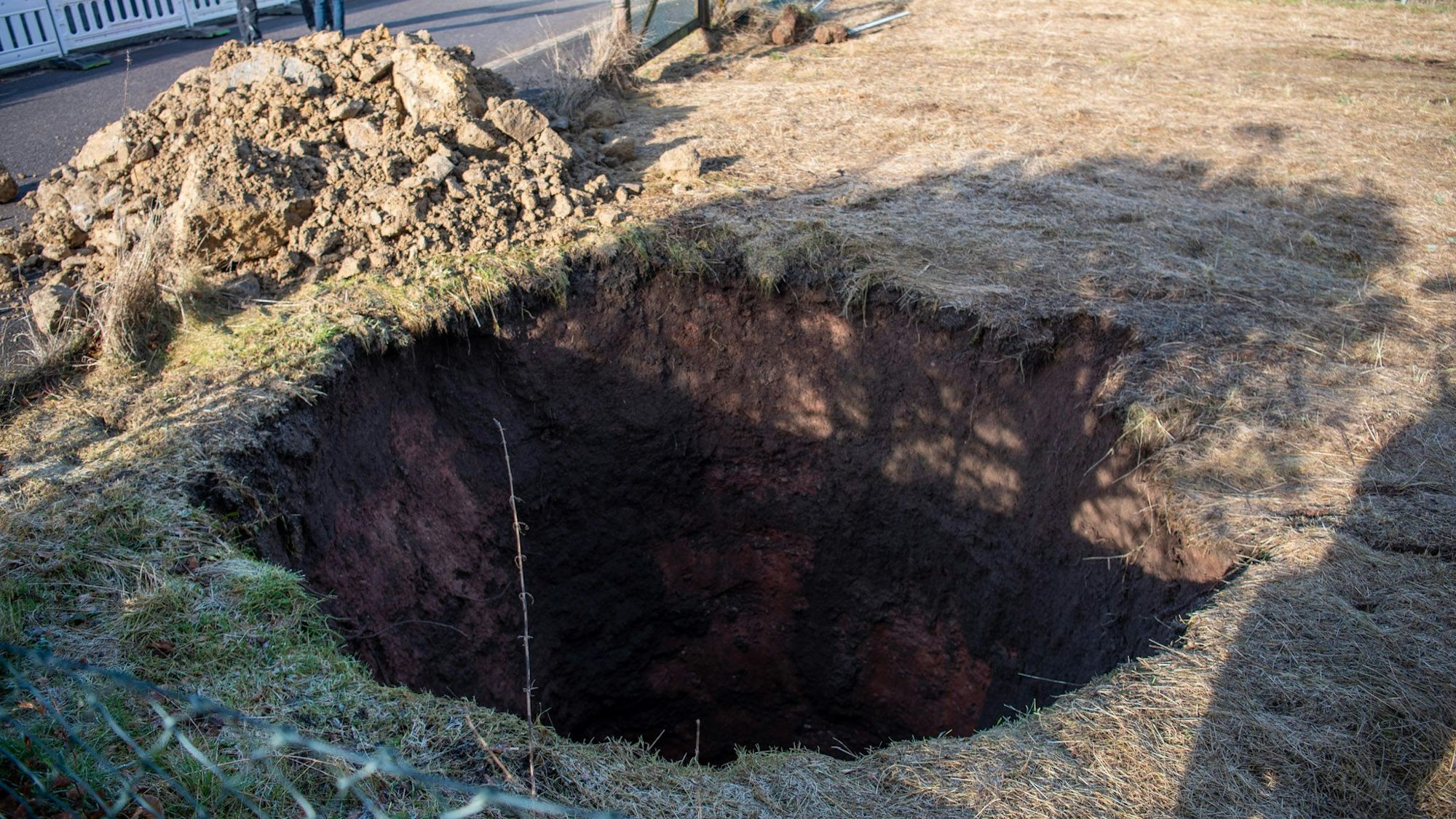 Auf dem Bild ist ein Loch auf einer Wiese zu sehen, dahinter liegt Geröll.