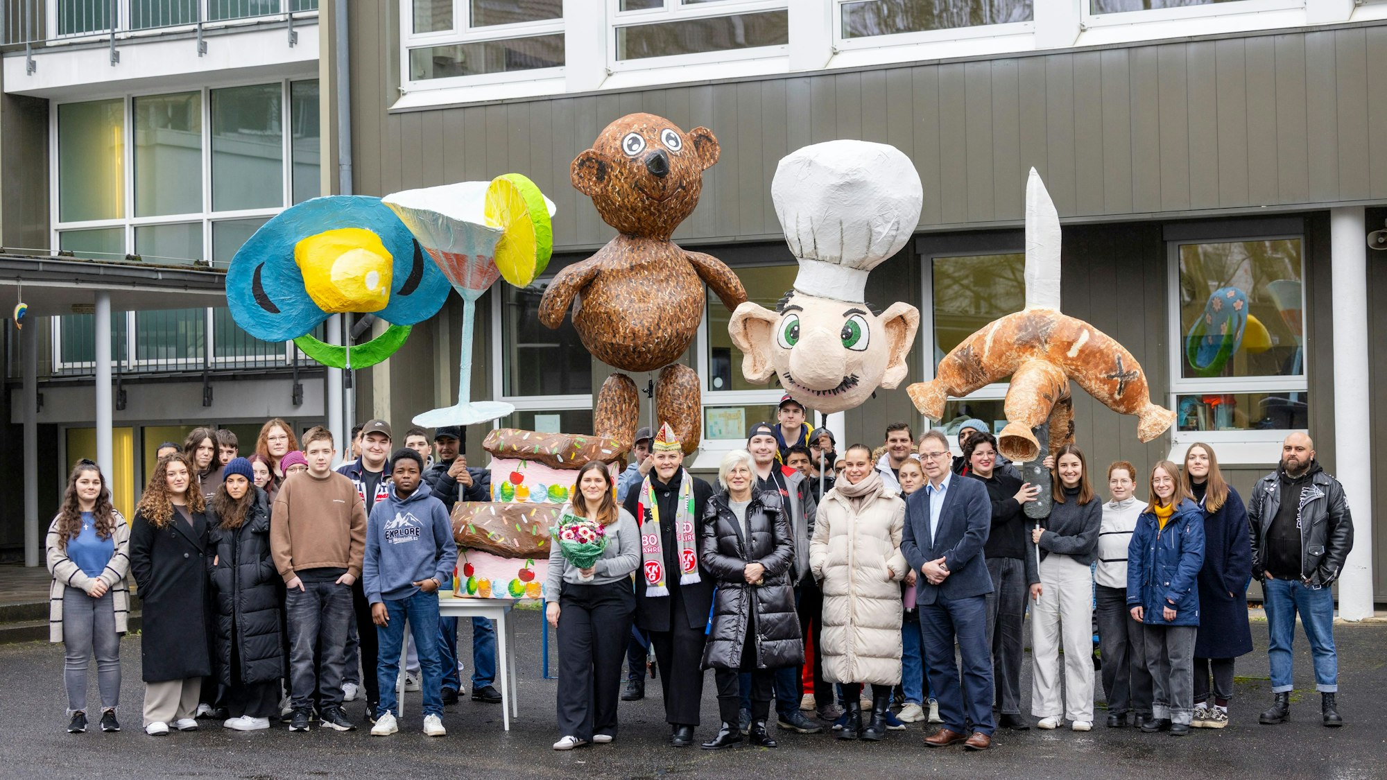 Stolz auf ihre Karnevalsfiguren: Schülerinnen und Schüler des Berufskollegs Ehrenfeld mit der projektleitenden Lehrerin Rebecca Lönhardt (mit Blumenstrauß) und Schulleiter Johannes Segerath (7.v.r.). Um zu gratulieren, kamen Simone Kropmanns (mit Kappe), Präsidentin der Kölnischen KG, und „KultCrossing“-Chefin Christa Schulte (rechts daneben).