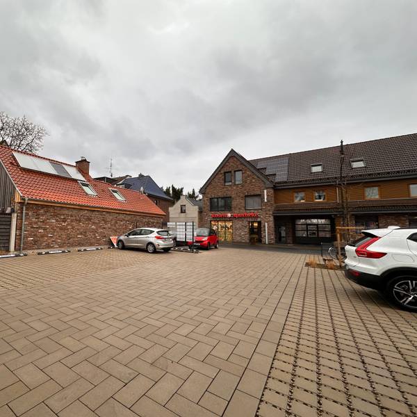 Auf einem großen Parkplatz stehen wenige Autos.