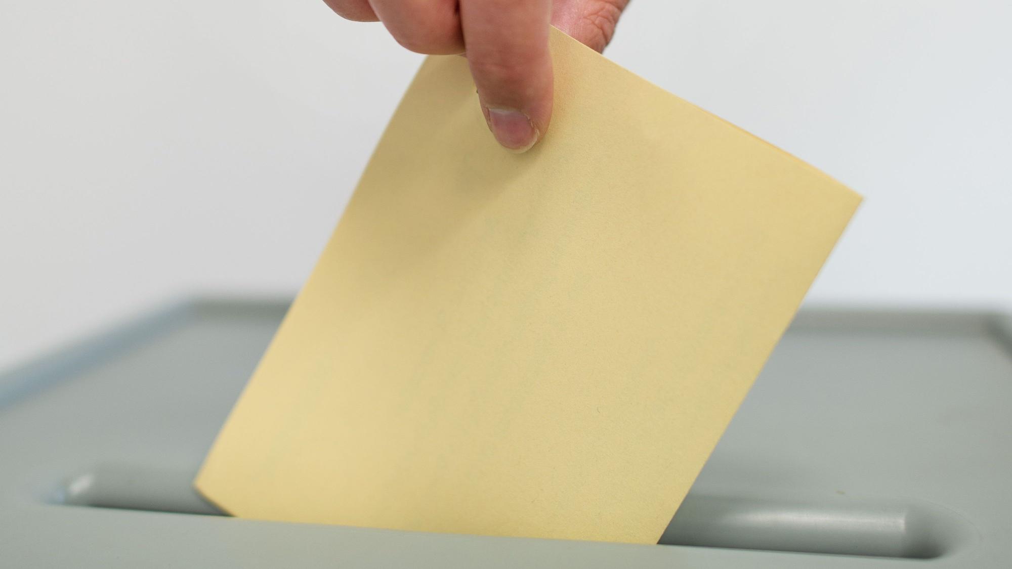 Ein Stimmzettel wird in eine Wahlurne geworfen. (Symbolbild)