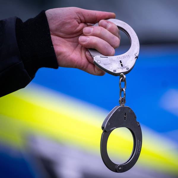 Ein Polizist hält während einer Verkehrskontrolle ein Paar Handschellen.