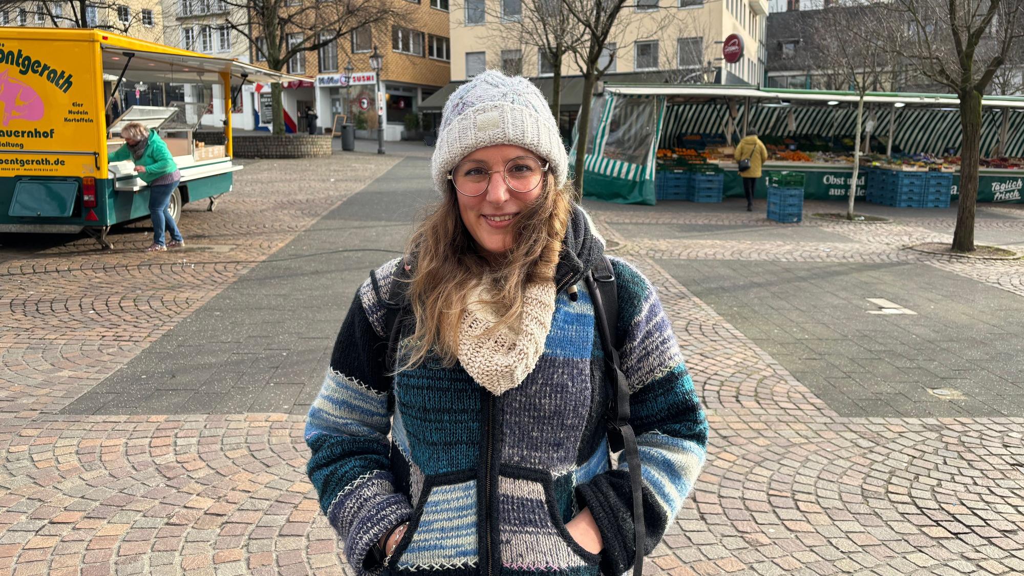 Eine junge Frau steht lächelnd auf dem Siegburger Marktplatz.