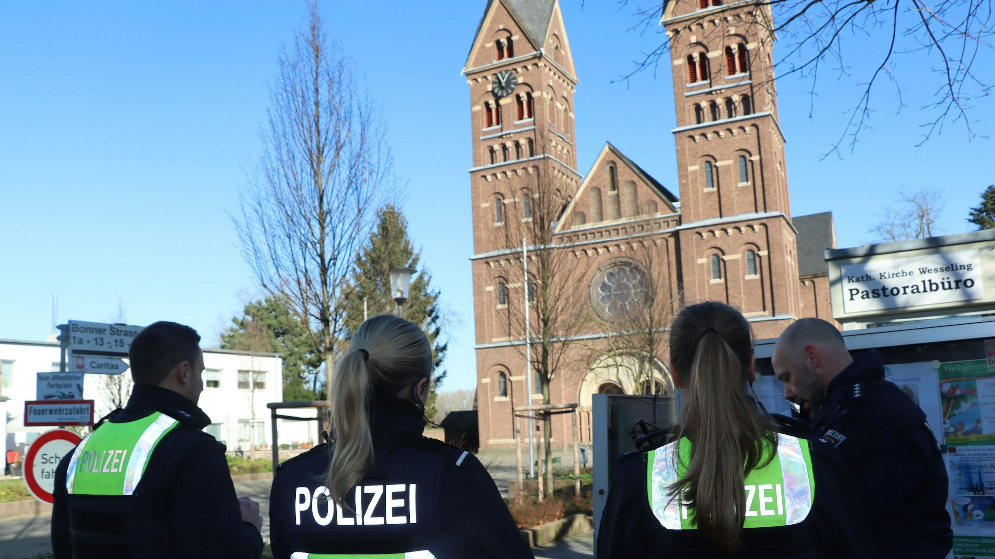 Polizeibeamte stehen auf dem Platz vor der Kirche St. Germanus in Wesseling.