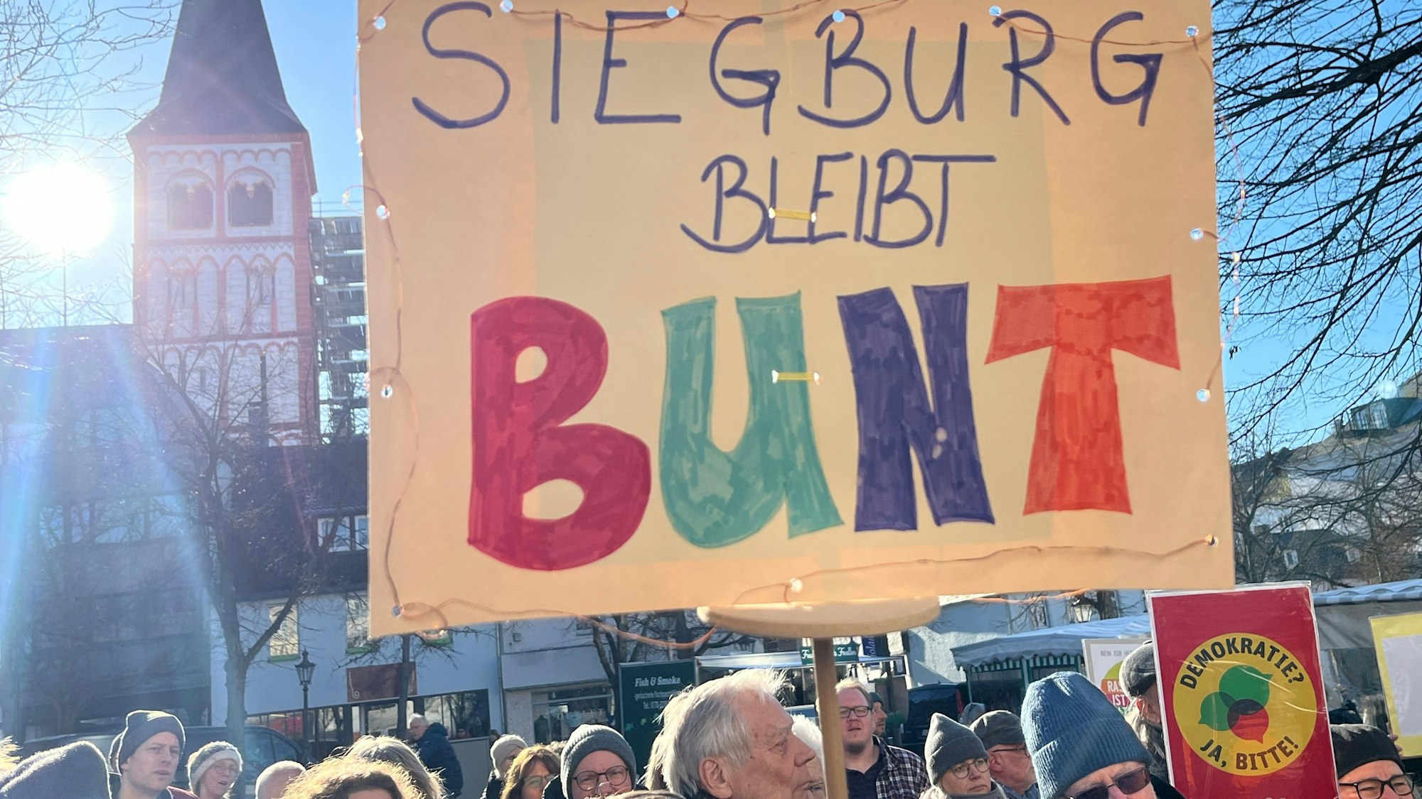 Menschen halten ein Plakat mit der Aufschrift „Siegburg bleibt bunt“.