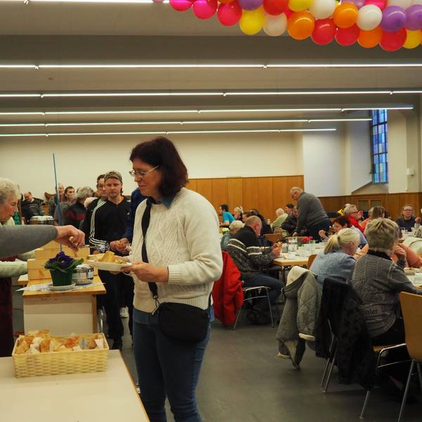 Helferinnen geben die Suppe aus. Eine Reihe von Gästen steht an. Die Tische im Raum sind gut gefüllt.