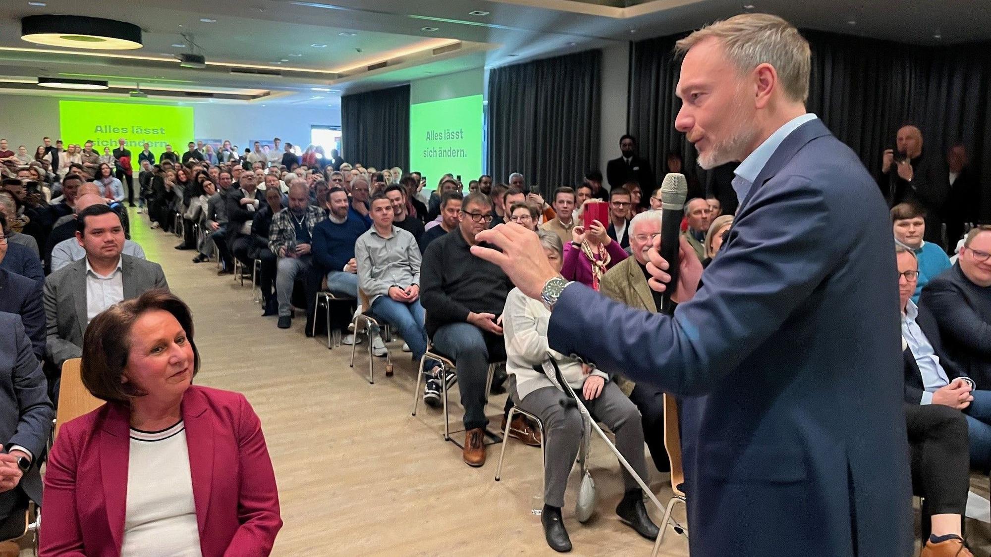 Ein Mann spricht vor vielen Zuschauern in ein Mikrofon.
