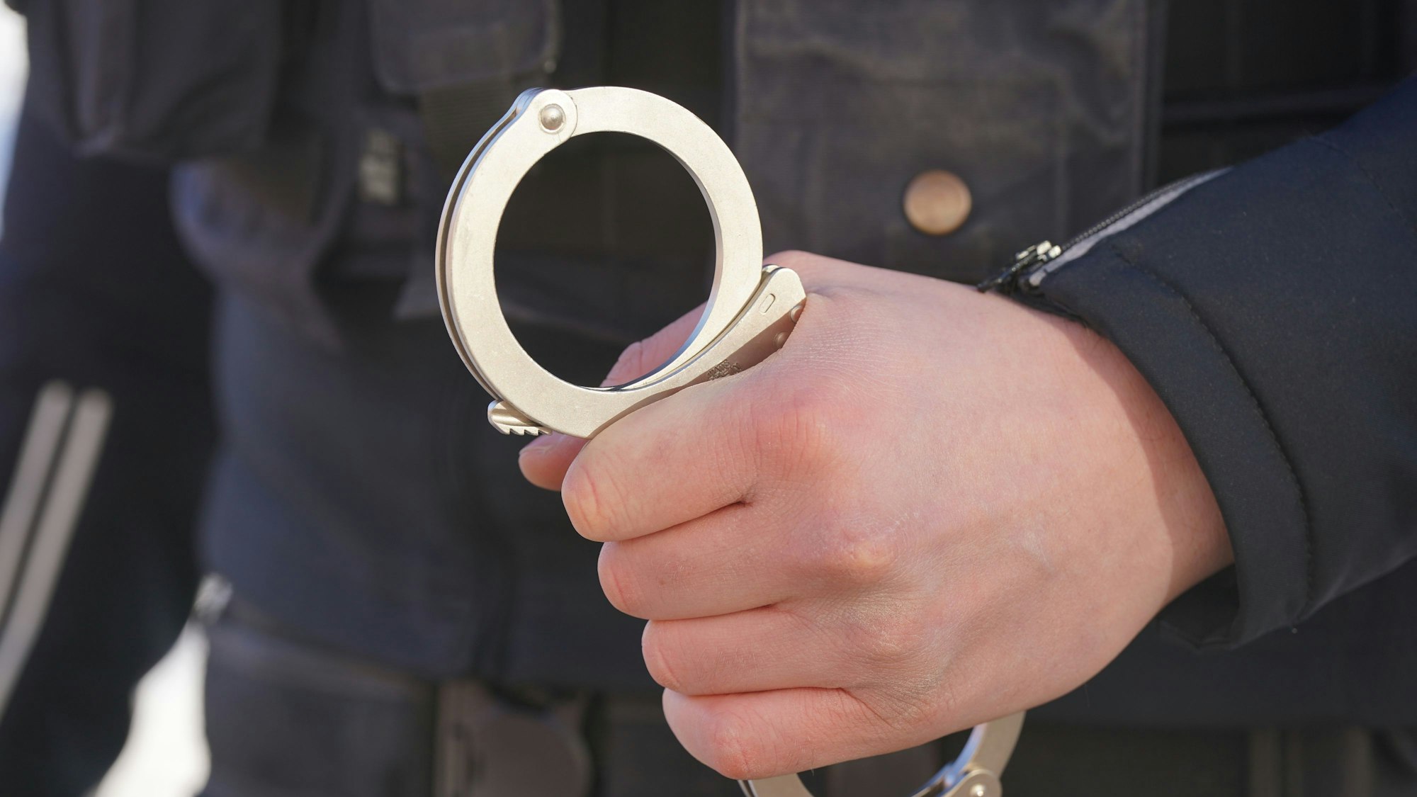 Das Symbolbild zeigt eine Handfessel in der Hand eines Beamten.