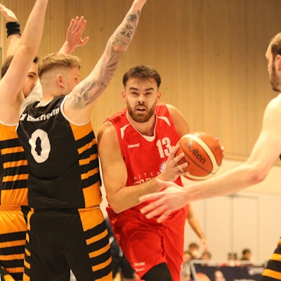 Erftbaskets-Spieler Marko Vojinovic hat den Ball in der Hand, drei Spieler stellen sich ihm entgegen.