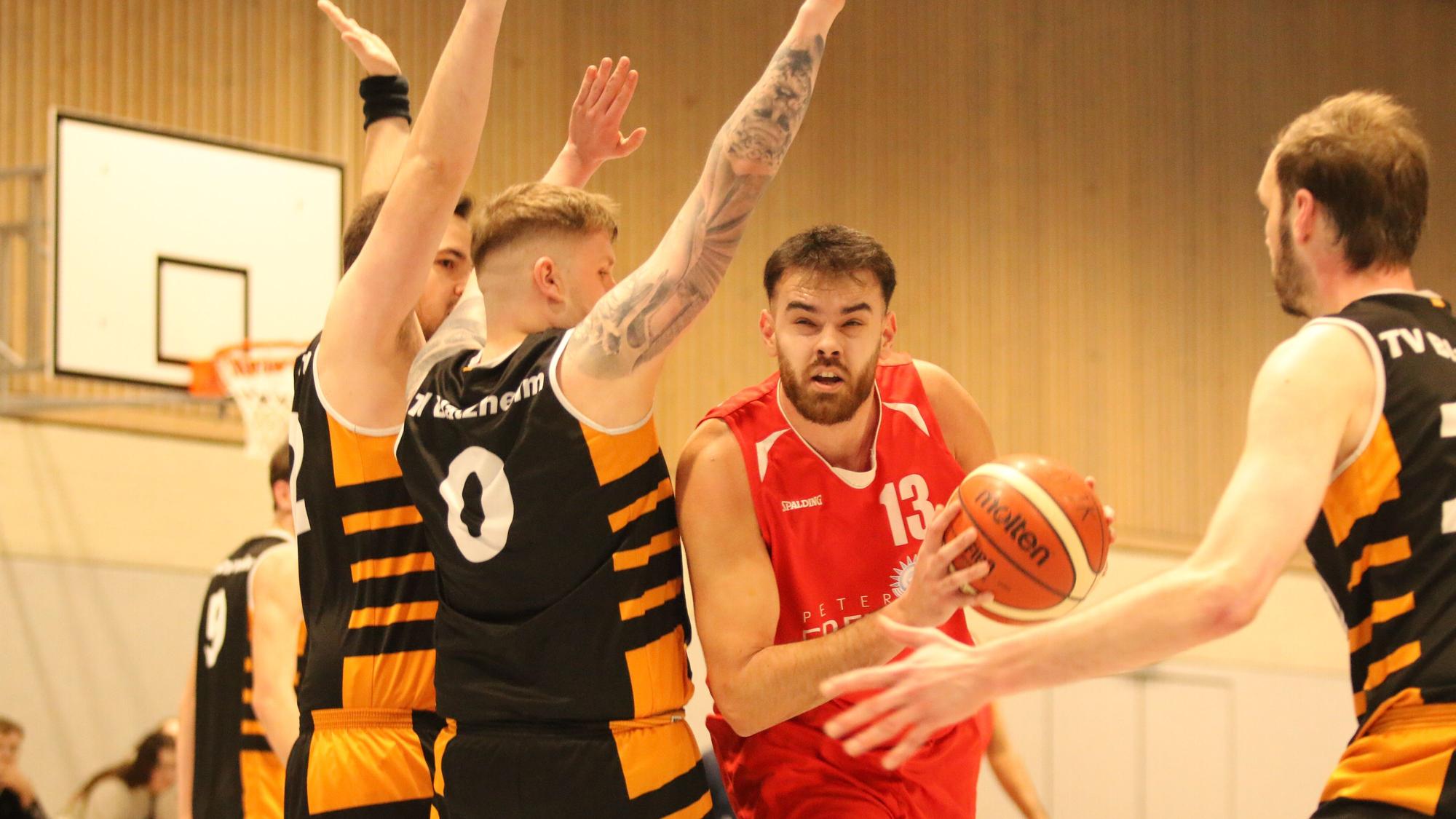 Erftbaskets-Spieler Marko Vojinovic hat den Ball in der Hand, drei Spieler stellen sich ihm entgegen.