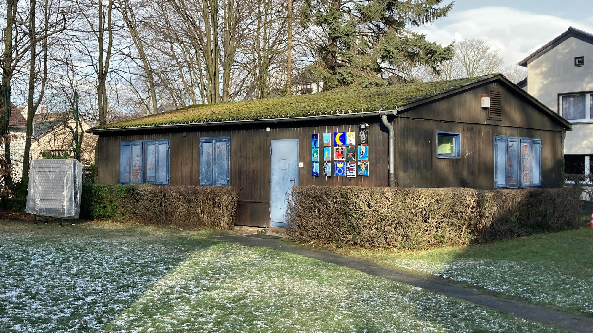 Ein braunes Blockhaus mit blauen Fensterläden und Türen.