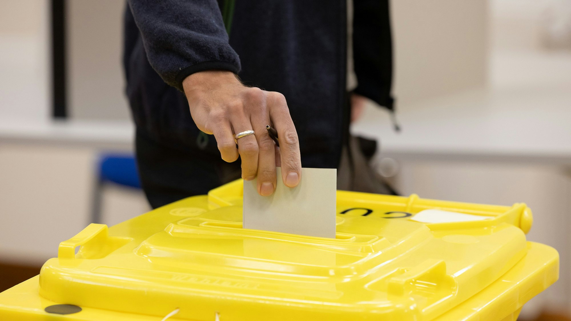 Eine Person wirft einen Umschlag in eine Wahlurne. (Symbolbild)