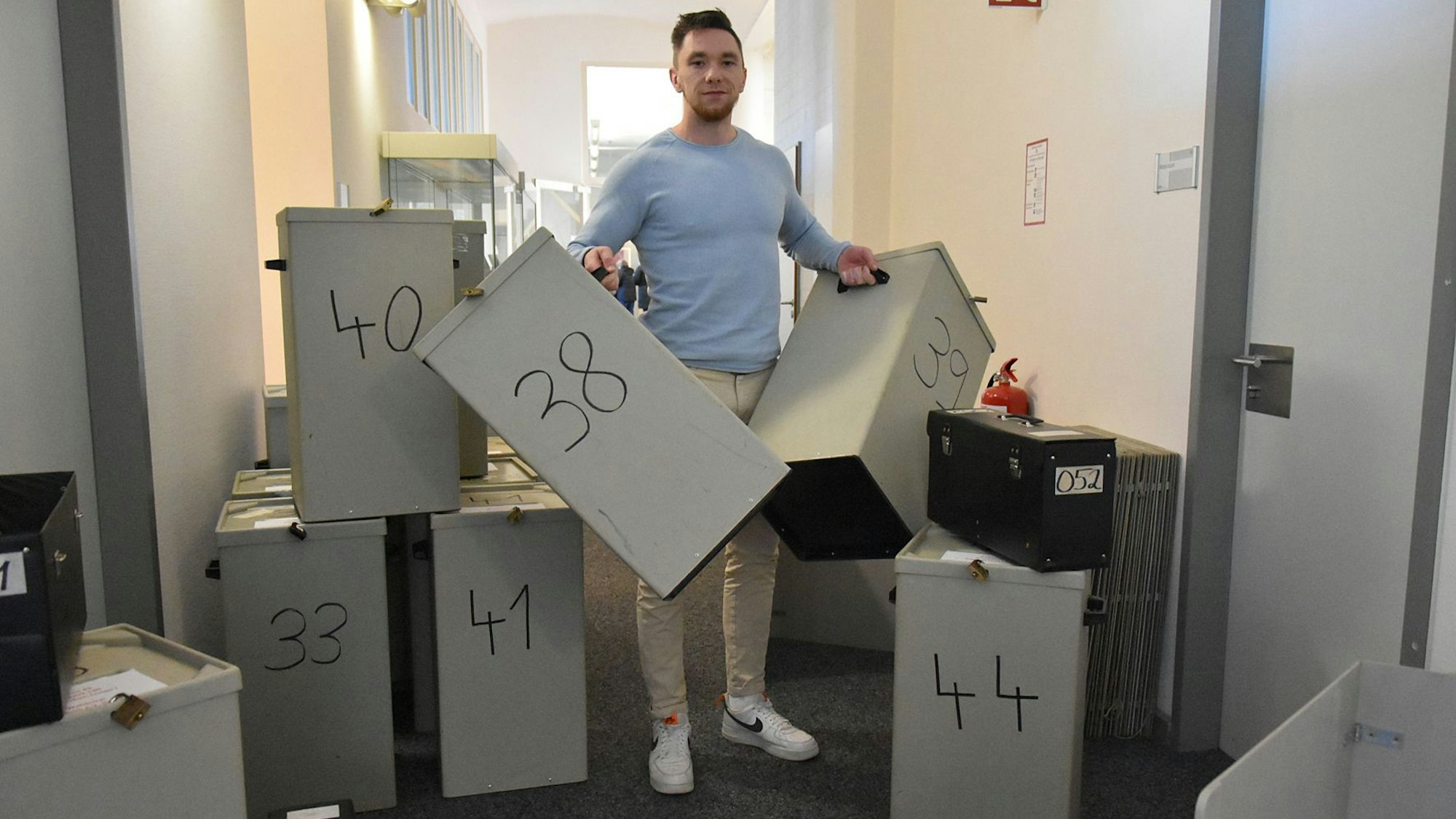 Ein Mann steht zwischen zahlreichen Wahlurnen.