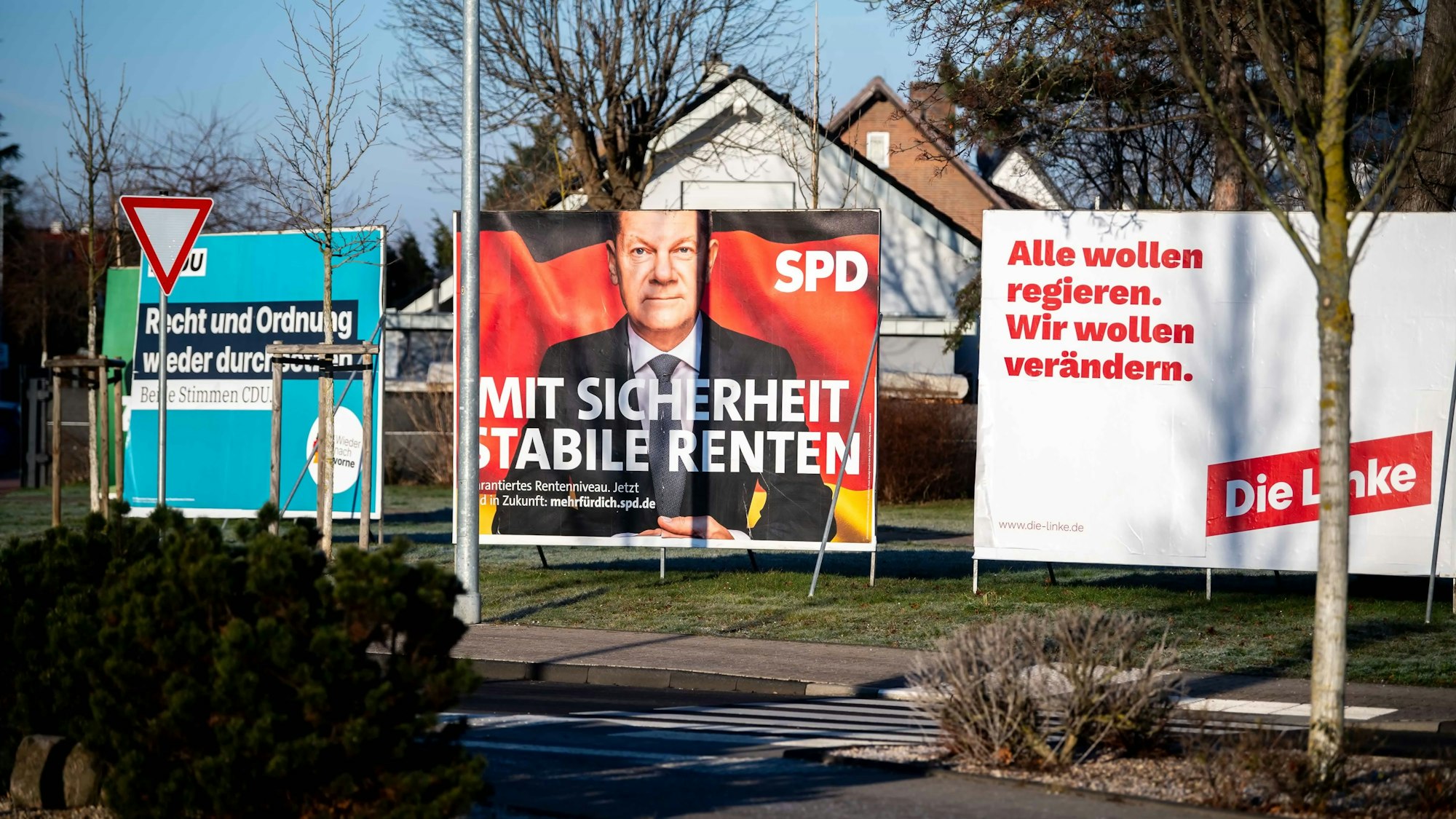 Mehrere Ständer mit Wahlplakaten stehen nebeneinander an einer Grünfläche.